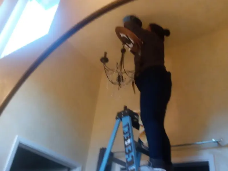 Electrician installing a chandelier in a Temecula residence